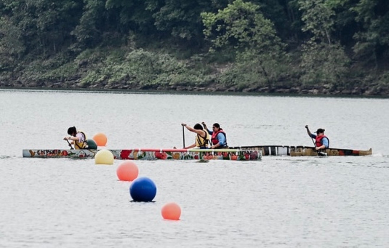 NYU paddlers racing Chrysalis alongside another canoe, with course buoys in the foreground